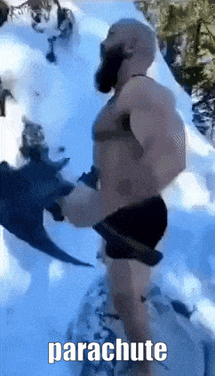 a man with a beard is standing in the snow holding a parachute .