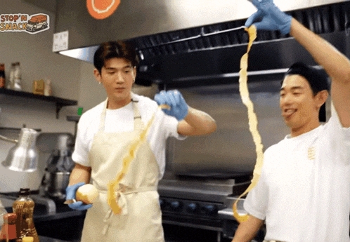 two men are peeling an onion in a kitchen with a stop in snack sign above them