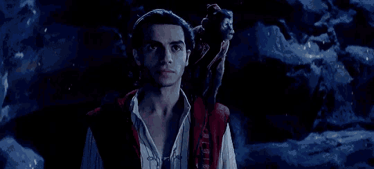 a man is holding a monkey on his shoulder in a cave .