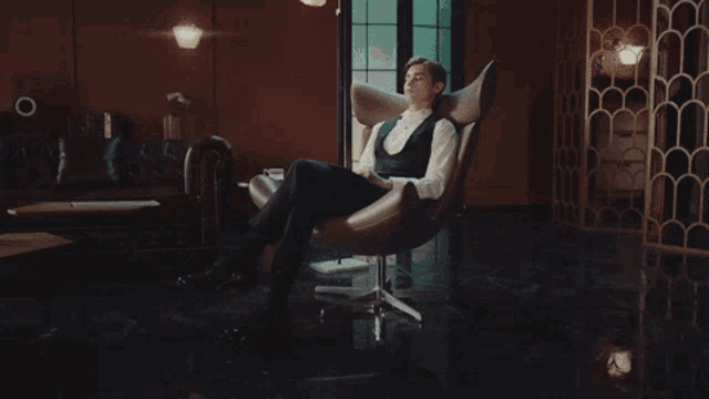 a man in a tuxedo is sitting in a chair looking at his phone
