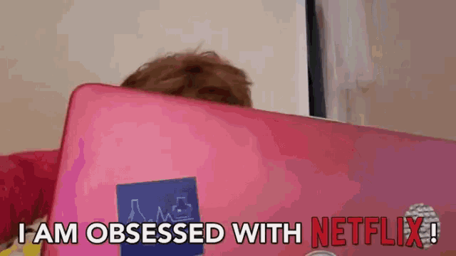 a person behind a pink laptop with the words i am obsessed with netflix