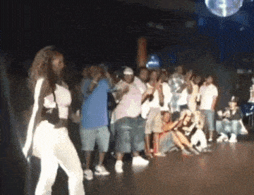 a woman is dancing in front of a crowd in a club