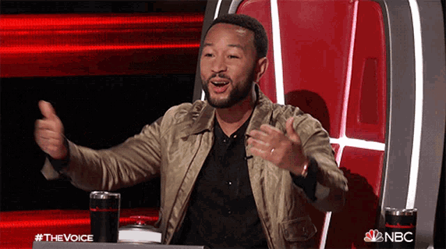 a man is giving a thumbs up while sitting in a chair with a nbc logo on it