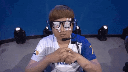 a man wearing glasses and a microphone is sitting in a room .