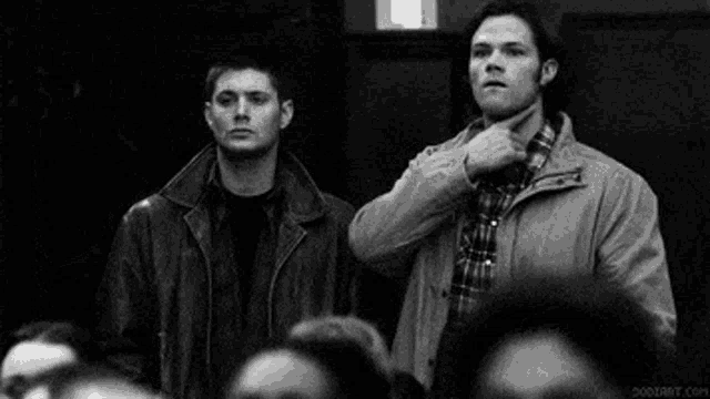 two men are pointing at each other in a crowd .