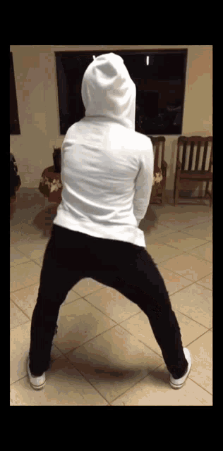 a person wearing a white hoodie and black sweatpants stands on their knees
