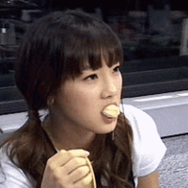 a girl with pigtails is eating a banana