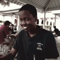 a young man wearing a black shirt with the word excelsior on it smiles