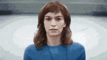 a woman wearing a blue shirt and a lanyard is looking at the camera .