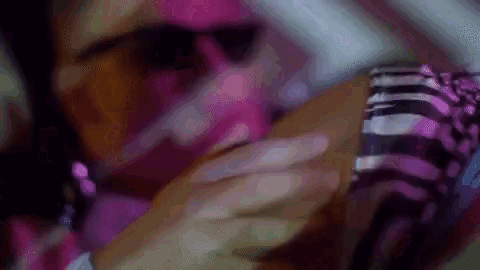 a woman wearing sunglasses and a pink scarf is looking at a cell phone .