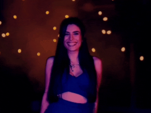 a woman in a black top is laughing in a dark room