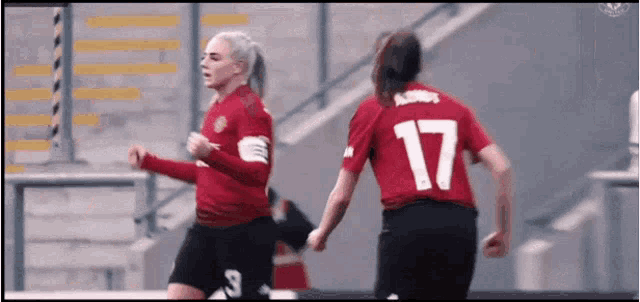 two female soccer players wearing red jerseys with the number 17 on the back