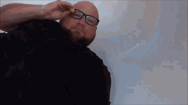 a bald man with glasses and a beard is laying on the floor .