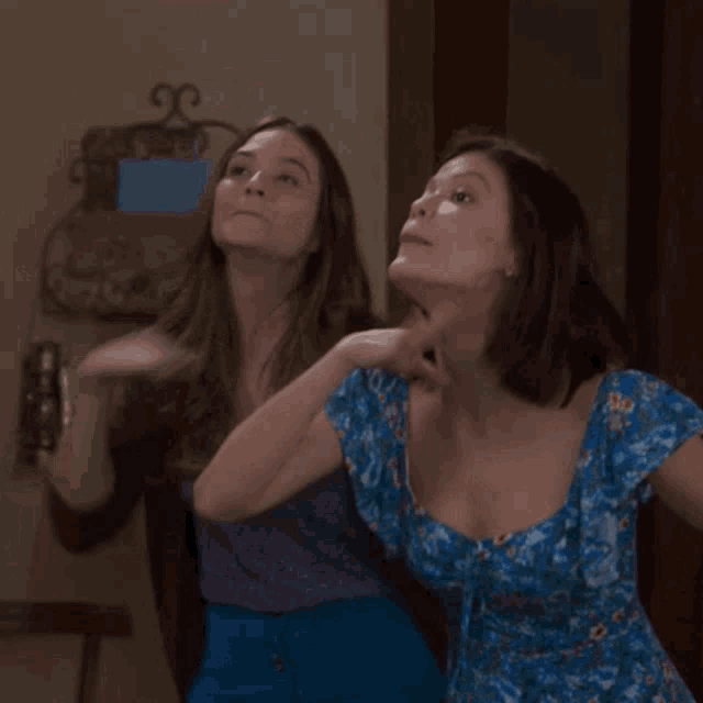 two women are standing next to each other with one wearing a blue dress