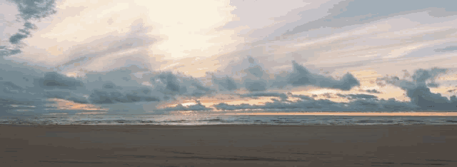 a beach with a cloudy sky and waves coming in