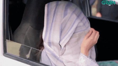 a woman in a hijab looks out of a car window with the word grun on the bottom right