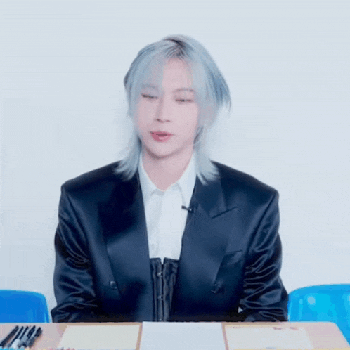 a man in a suit is sitting at a desk with pencils on it