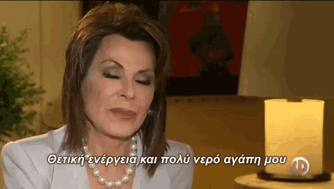 a woman wearing a pearl necklace talks in a foreign language