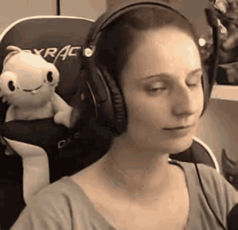 a woman wearing headphones is sitting in a chair with a stuffed animal on the back ..