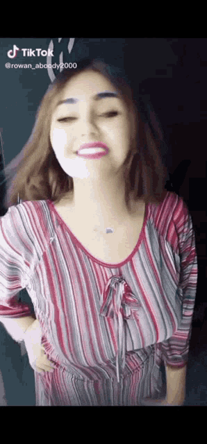 a woman in a red and gray striped shirt is dancing and smiling .