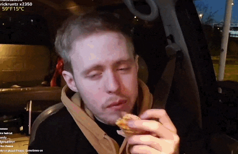 a man is eating a piece of pizza in a car while rickruttz is watching