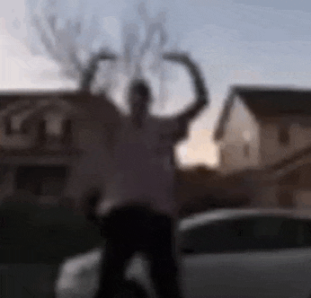 a blurry picture of a person standing in front of a car in a parking lot .