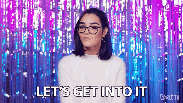 a woman wearing glasses is saying `` let 's get into it '' while standing in front of a curtain .