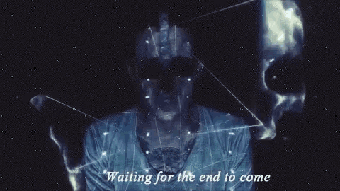 a man is standing in the dark with the words `` waiting for the end to come '' behind him .