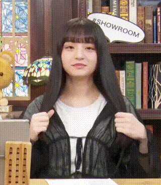 a woman with long black hair is sitting at a table with a sign that says showroom .