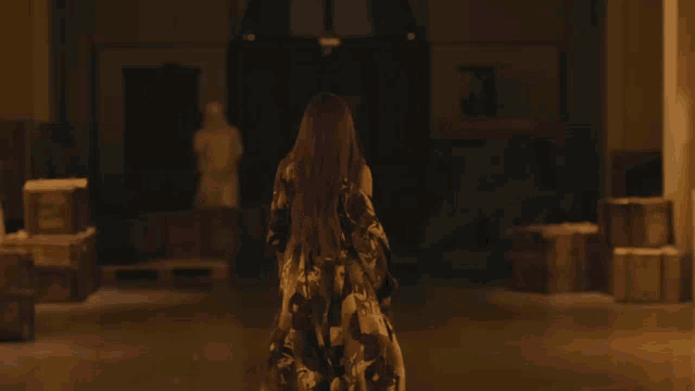a woman with long hair is walking through a dark room