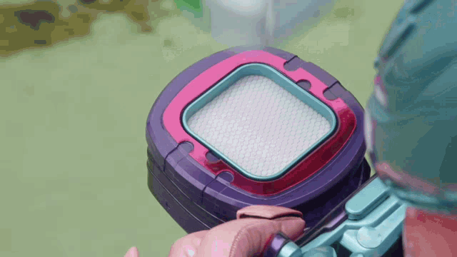 a person is holding a purple and pink device that looks like a phone
