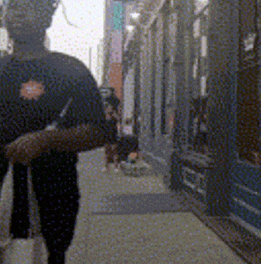 a person wearing a black shirt with a star on the back walks down a sidewalk
