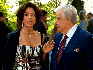 a woman in a striped dress talks to a man in a suit