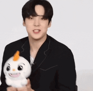 a young man in a black suit is holding a stuffed animal .