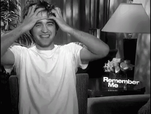 a black and white photo of a man with his hands on his head in front of a sign that says remember me