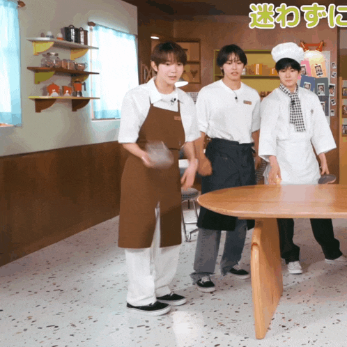 three men in aprons are standing around a table with chinese writing on the wall