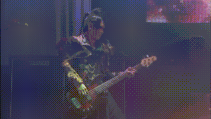 a man is playing a bass guitar in front of a screen