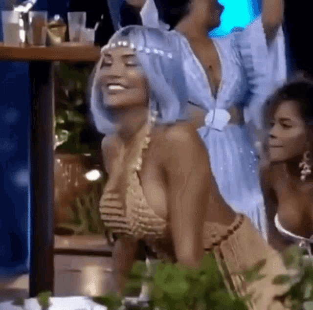a woman wearing a blue wig and a gold top is dancing in a crowd of people .