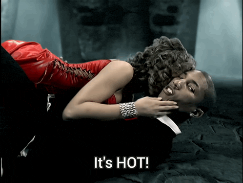 a woman in a red dress is laying on top of a man in a suit and the words it 's hot are visible