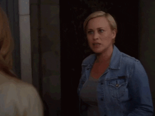 a woman in a denim jacket is standing next to another woman in a white shirt