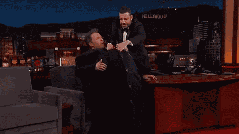 two men are hugging each other on a couch .