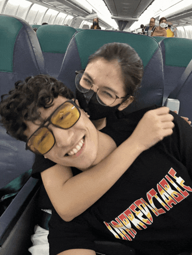 a girl wearing a black mask is hugging a boy wearing a black shirt that says incredible