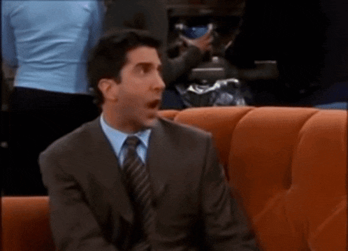 a man in a suit and tie sitting on a couch reading a book