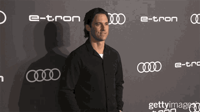 a man stands in front of a wall that says e-tron on it