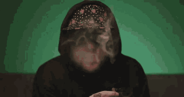 a man in a hooded sweatshirt is smoking a cigarette .