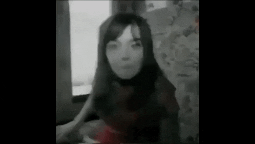 a black and white photo of a woman sitting on a bed .