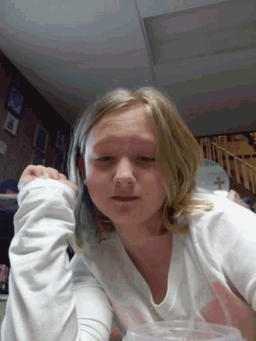 a girl in a white shirt with a pink heart on it looks at the camera
