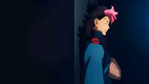 a man with long black hair and pink streaks is standing in the dark