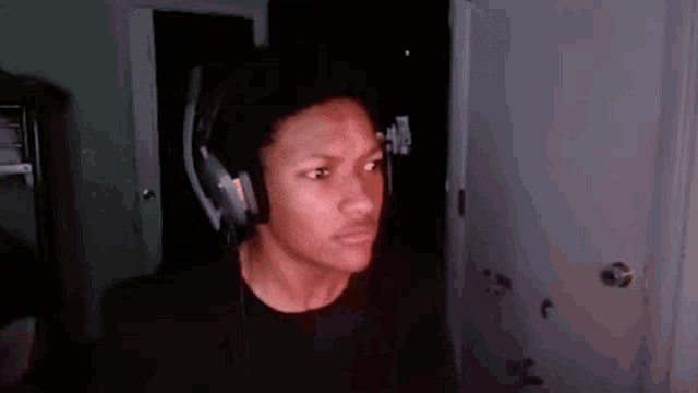 a young man wearing headphones is standing in front of a computer screen .