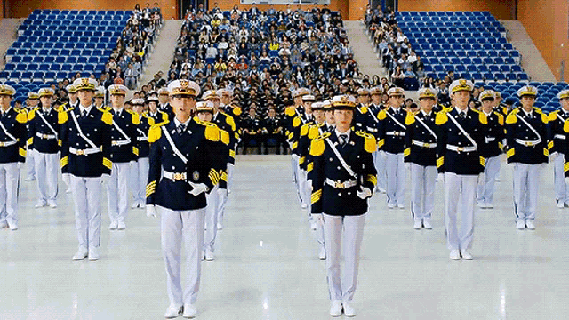 a group of soldiers march in front of a crowd